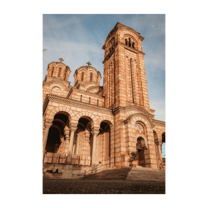 Inquadratura dal basso di un'ornata chiesa in pietra con un alto campanile e cupole contro un cielo blu.