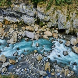 Vue aérienne en pose longue d'une rivière turquoise coulant impétueusement à travers des gorges rocheuses parsemées de gros rochers.