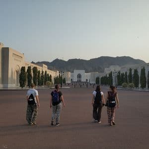 Un viaje en grupo de WeRoad cruza una gran plaza hacia un gran edificio con montañas al fondo.