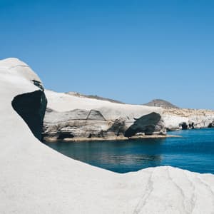 Formazioni rocciose bianche e lisce costeggiano un mare blu calmo sotto un cielo sereno.