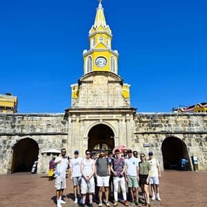 Eine WeRoad-Gruppe posiert für ein Foto vor einem Steintor mit einem markanten gelben Glockenturm.