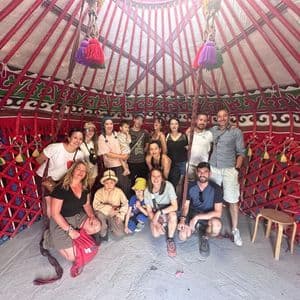 Un voyage de groupe WeRoad prend la pose pour une photo à l'intérieur d'une yourte rouge, traditionnelle et richement décorée.