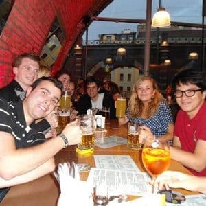 Un voyage de groupe WeRoad avec des gens souriants devant l'appareil photo, attablés dans un pub avec des verres de bière.