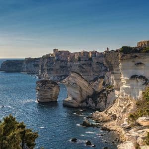 Una città costiera costruita in cima a scogliere bianche a picco che si tuffano nel mare blu in una giornata di sole.