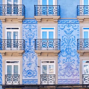 La facciata di un edificio decorato con piastrelle azulejo a motivi blu e bianchi e piccoli balconi con ringhiere in ferro battuto.