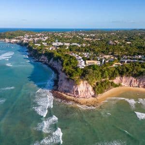 Veduta aerea di una cittadina costiera costruita su lussureggianti scogliere a picco su una spiaggia sabbiosa e sull'oceano.