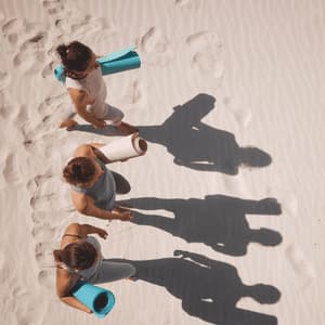Una vista aérea de tres personas de un viaje en grupo de WeRoad caminando sobre la arena, llevando esterillas de yoga enrolladas y proyectando largas sombras.
