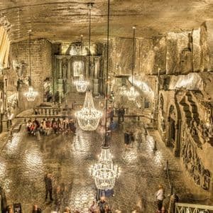 Una vista dall'alto di un'ampia cavità sotterranea scavata nella roccia, con sfarzosi lampadari che illuminano i turisti su un pavimento riflettente.