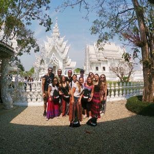 Un groupe WeRoad pose pour une photo dans une cour de gravier, devant un temple orné et entièrement blanc, par une journée ensoleillée.