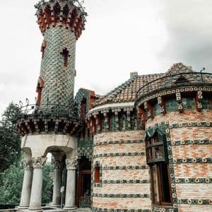 Un edificio decorato con un'alta torre rivestita di tegole verdi e rosse e muri in mattoni con motivi decorativi.