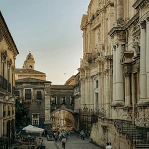Una strada stretta in una città storica con palazzi ornati, un caffè all'aperto e gente che passeggia.