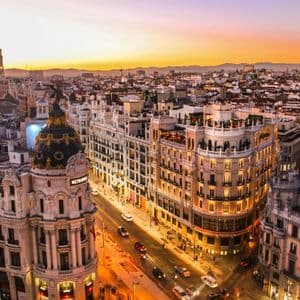 Une vue aérienne d'un vaste paysage urbain européen au coucher du soleil, avec des bâtiments ornés et la circulation dans les rues.