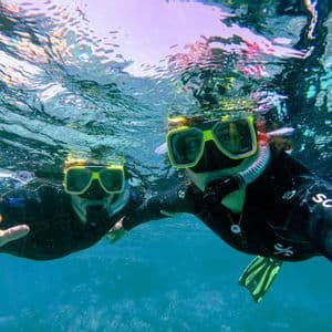Due persone in viaggio di gruppo WeRoad si scattano un selfie subacqueo con maschere da snorkeling in acqua cristallina.