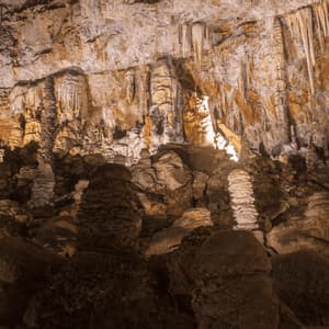Una vasta grotta sotterranea piena di stalattiti e stalagmiti illuminate.