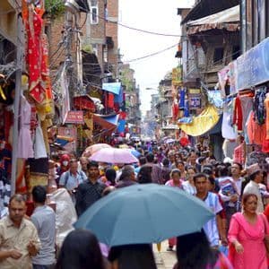 Une foule de gens marchant dans une rue de marché extérieur étroite et animée, bordée de boutiques et de marchandises colorées.