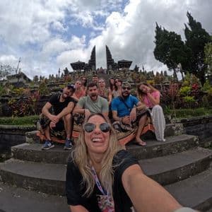 Un gruppo WeRoad si scatta un selfie giocoso sui gradini di un complesso di templi ornato sotto un cielo nuvoloso.
