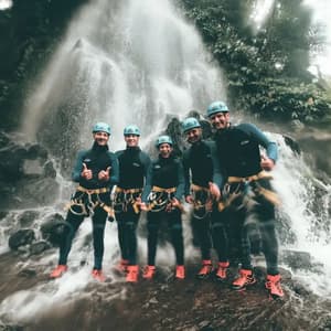 Un grupo de WeRoad, con trajes de neopreno y cascos, sonríe para una foto sobre rocas frente a una cascada.
