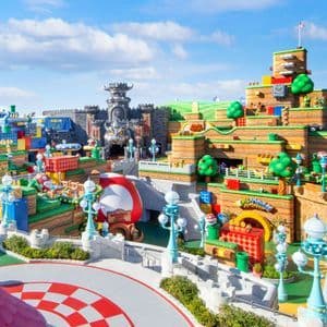 Una panoramica colorata del parco a tema Super Nintendo World, con castelli iconici, tubi verdi e strutture a blocchi sotto un cielo soleggiato.