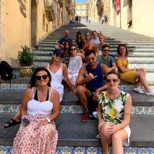Un voyage de groupe WeRoad posant pour une photo sur un large escalier extérieur avec des carreaux colorés et décoratifs.