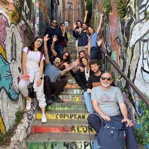 Un voyage de groupe WeRoad posant pour une photo sur un escalier extérieur coloré entouré de murs recouverts de graffitis.