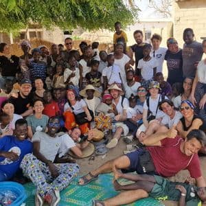 A WeRoad group trip and a local community with many children pose together for a photo in a village.