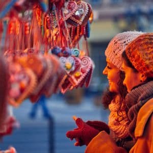 Due donne, con caldi cappelli e sciarpe invernali, osservano biscotti di pan di zenzero colorati a forma di cuore appesi a una bancarella del mercato.