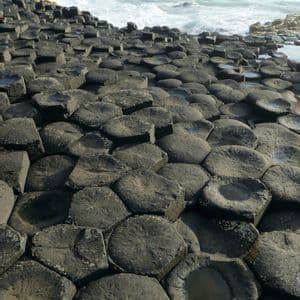 Des colonnes de basalte hexagonales imbriquées forment un dallage naturel qui rencontre la mer agitée avec des vagues aux crêtes blanches.
