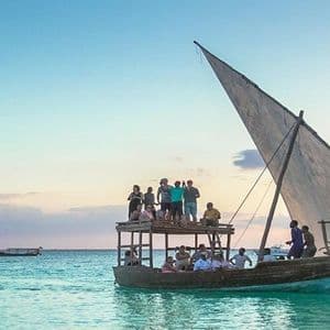 Un voyage de groupe WeRoad en voilier sur un boutre traditionnel en bois à deux ponts, sur des eaux turquoise au coucher du soleil.