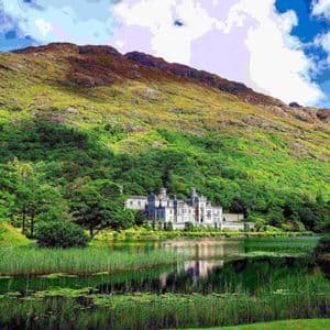 Un castello di pietra si erge sulla riva di un lago, annidato alla base di una grande montagna verde sotto un cielo parzialmente nuvoloso