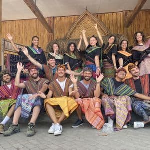 Eine WeRoad Gruppenreise, die für ein Foto posiert, alle lächeln und tragen farbenfrohe traditionelle Kleidung.