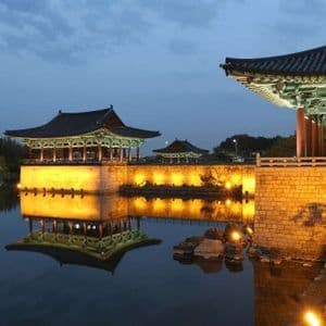 I padiglioni tradizionali coreani sono splendidamente illuminati al tramonto, con i loro riflessi che si specchiano sulle calme acque circostanti.
