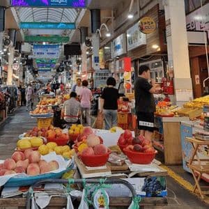 Vista su un vivace corridoio di un mercato coperto, con bancarelle che vendono frutta fresca come le pesche in primo piano.