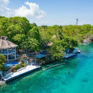 Vista aerea di un gazebo con tetto di paglia e di un resort su una costa lussureggiante e tropicale con acqua cristallina e turchese.