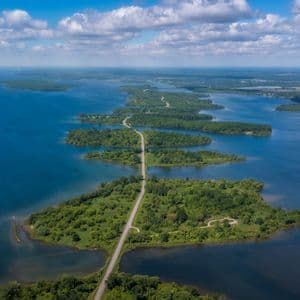 Vista aérea de una larga carretera elevada que conecta una cadena de exuberantes islas verdes a través de un amplio cuerpo de agua azul.