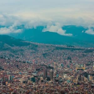 Una vista panorámica de una ciudad densa anidada en un valle entre montañas bajo un cielo nublado.