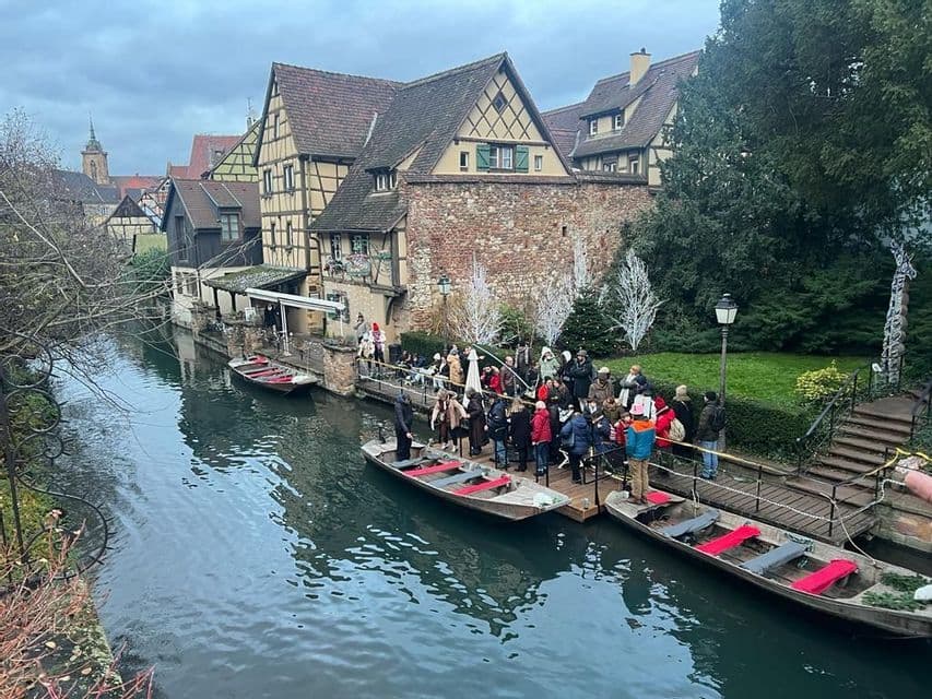 Un grupo de WeRoad se reúne en un muelle junto a barcos de canal en un pueblo histórico con edificios de entramado de madera.