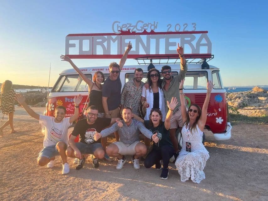 Eine WeRoad-Gruppe posiert und lächelt für ein Foto vor einem roten und weißen Oldtimer-Van mit einem 'Formentera'-Schild.