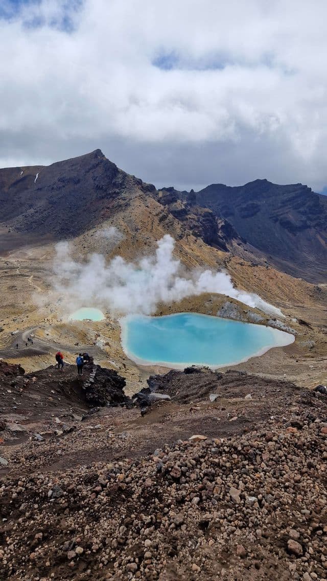 Un viaggio di gruppo WeRoad con trekking in un paesaggio roccioso e vulcanico, caratterizzato da due laghi geotermici turchesi che emettono vapore.