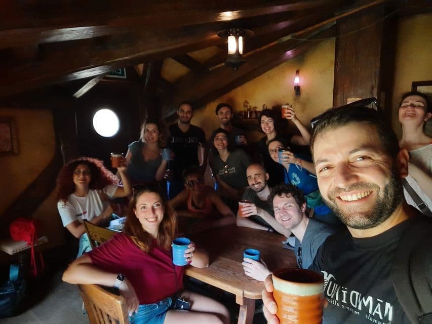 Un gruppo WeRoad si scatta un selfie, sorridendo e brindando con i boccali, all'interno di un'accogliente taverna rustica con travi in legno.
