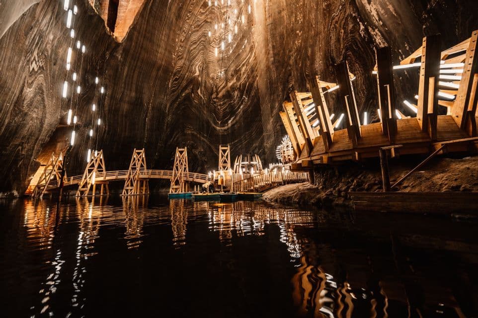 Un lago subterráneo dentro de una gran mina de sal iluminada con estructuras de madera y un puente.