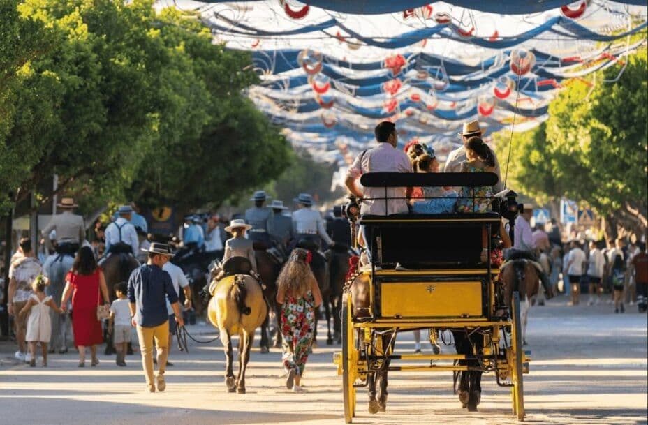 Una strada affollata con persone che camminano, cavalcano e in una carrozza gialla sotto stendardi decorativi blu e bianchi.