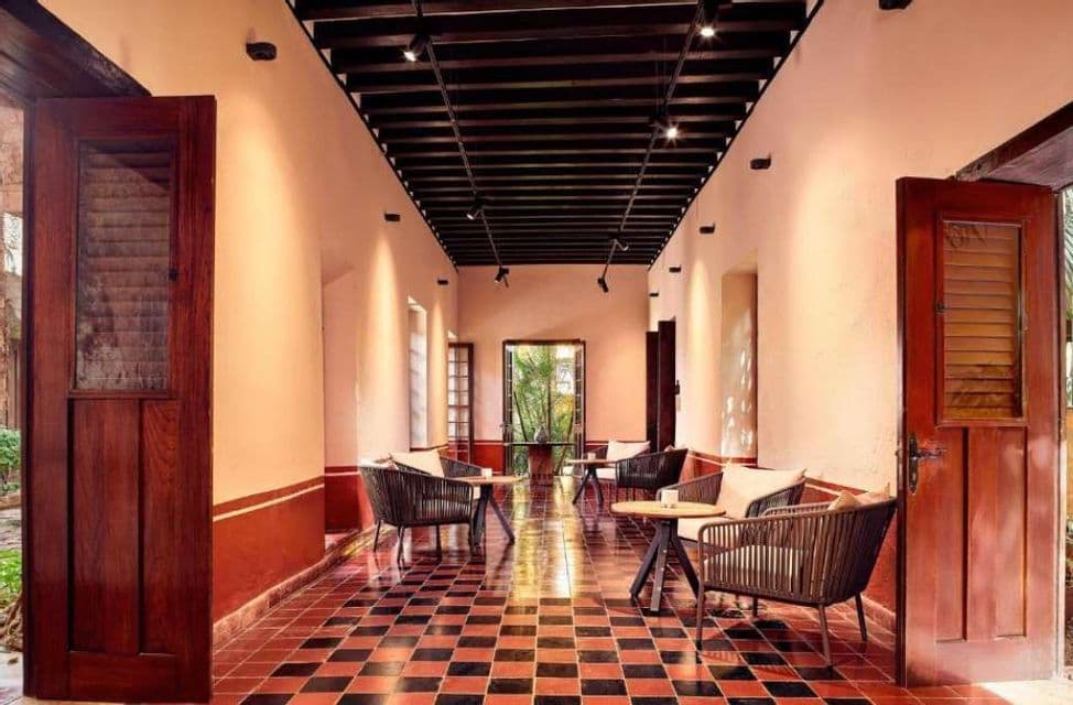 Un corridoio coperto vuoto con sedie e tavoli in vimini su un pavimento a scacchi rossi e neri.