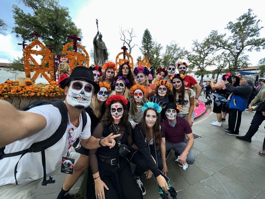 Un gruppo WeRoad si scatta un selfie con i volti dipinti come teschi calavera in una piazza durante un festival.