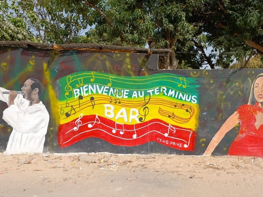 Un mural colorido con temática rasta en una pared anuncia el 'Terminus Bar' con cantantes y notas musicales.