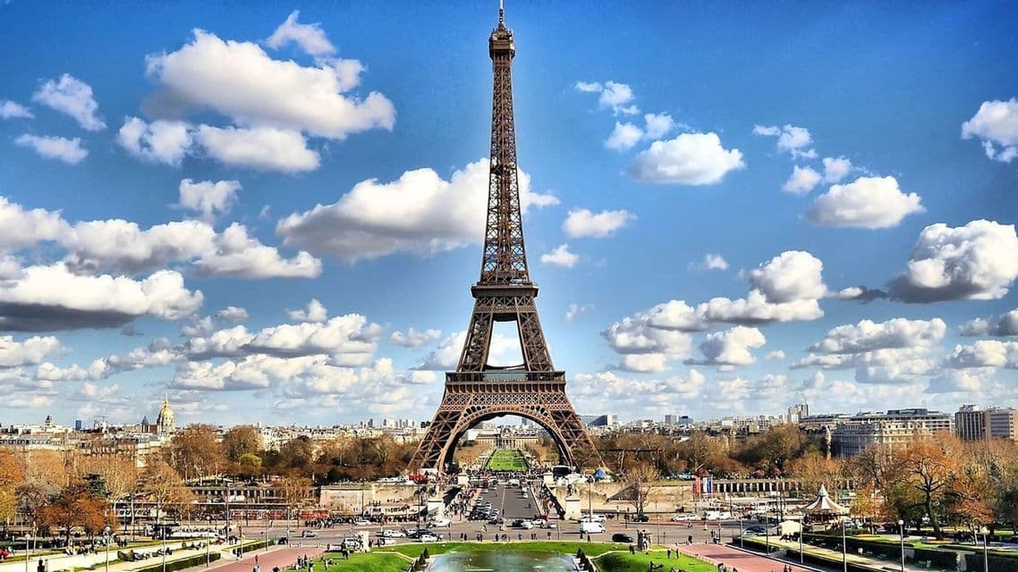 Una vista diurna della Torre Eiffel che si erge sul panorama di Parigi sotto un cielo blu pieno di nuvole bianche