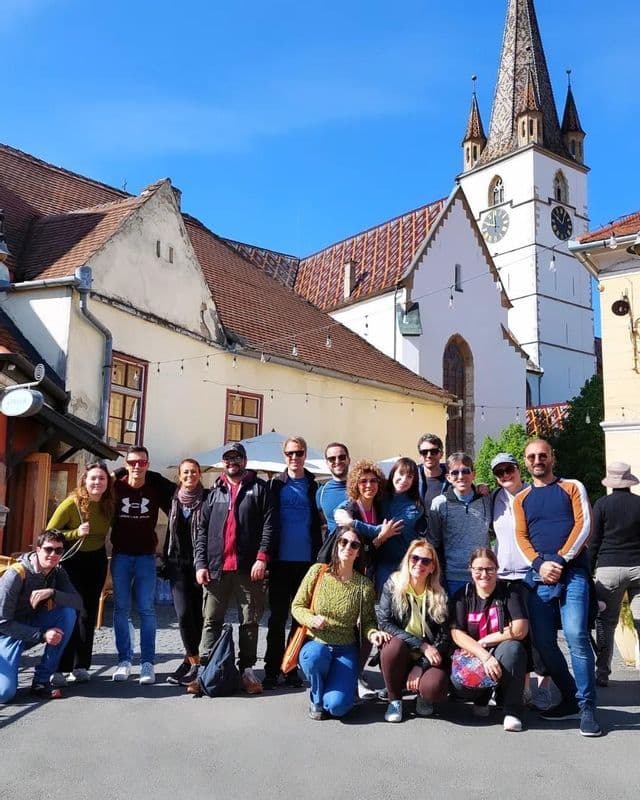 Eine WeRoad-Gruppe posiert für ein Foto auf einem sonnigen Stadtplatz mit einer weißen Kirche im Hintergrund.