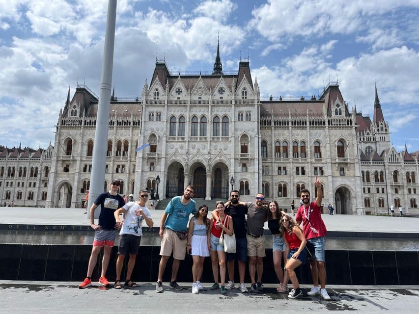 Un viaje en grupo de WeRoad de nueve personas posando para una foto en una gran plaza frente a un edificio gubernamental ornamentado bajo un cielo nublado.