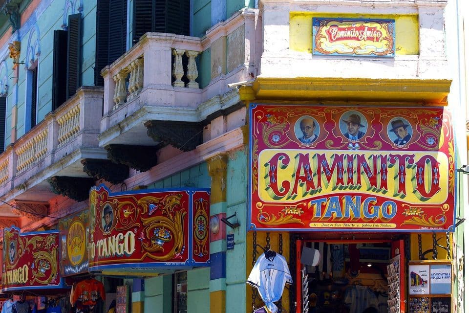 Facciate colorate di edifici con balconi decorati e grandi insegne vivaci per 'Caminito Tango' sopra l'ingresso di un negozio di souvenir