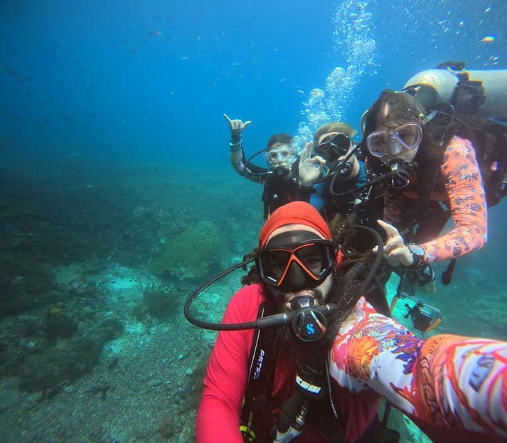 Un viaje en grupo de WeRoad se toma una selfie bajo el agua mientras bucean sobre un arrecife de coral.