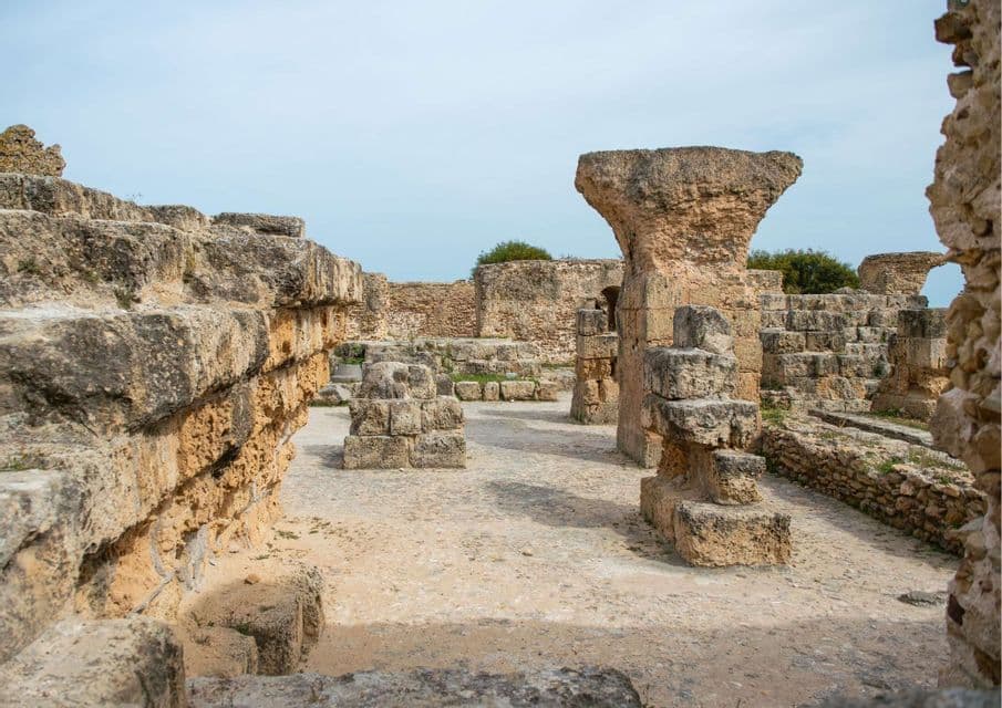 Antiguas ruinas de piedra con muros desmoronados y la base de una gran columna en un sitio arqueológico